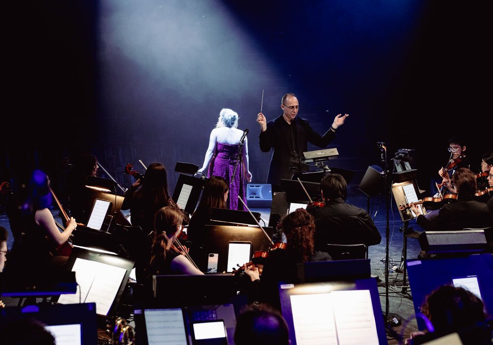 Conductor leading the Theatrical Symphony ensemble during a live performance